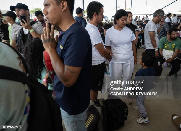 Elizabeth Rodriguez and her husband Balbino Flores from Venezuela watch their son Melvyn Flores as they wait for a bus to New York City at Mission:...