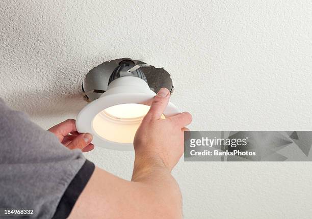 installing led retrofit bulb into ceiling fixture - illuminated stock pictures, royalty-free photos & images
