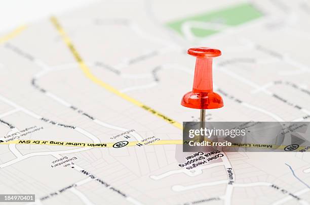 a red push pin stuck in a street map - pin up stockfoto's en -beelden