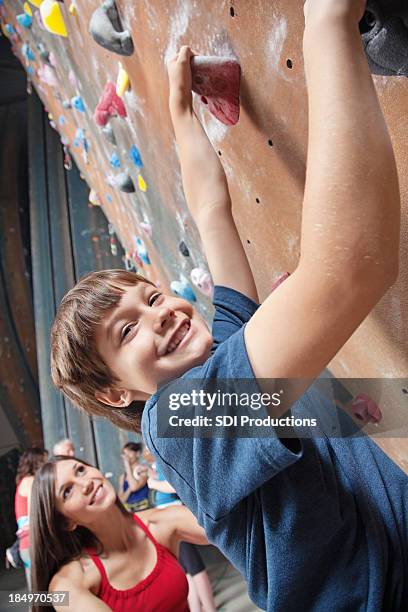 junge indoor-klettern mit seinem trainer - boy rock climbing stock-fotos und bilder