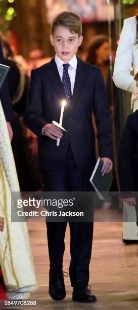Prince George of Wales holds a candle as he leaves with his family at The "Together At Christmas" Carol Service at Westminster Abbey on December 08,...