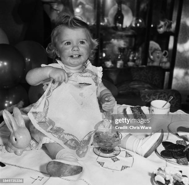 Margaret Harding sitting on the table to eat jelly on her first birthday in North London, December 1948.