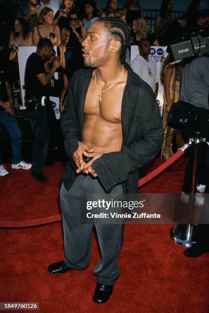 American singer and songwriter D'Angelo, wearing an open black shirt with his chest exposed, attends the 2000 MTV Movie Awards, held at Sony Pictures...