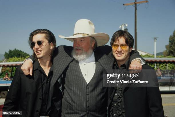 American singer, songwriter and musician Charlie Daniels, his arms around two men in black suits with black shirts, attends the 34th Annual Academy...