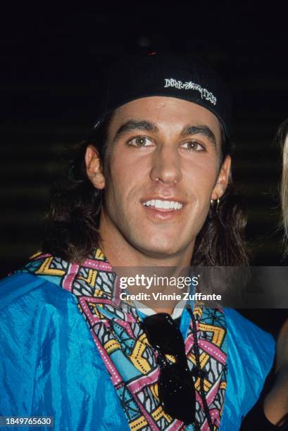 American actor Dan Cortese, wearing a baseball cap reversed, with sunglasses hanging from the collar of his blue shirt, during MTV's 2nd Annual Rock...
