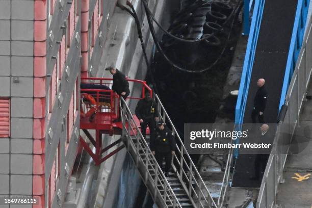 Police officers walk down the steps of the Bibby Stockholm Barge as a body is brought out on a gurney on December 12, 2023 in Portland, England....