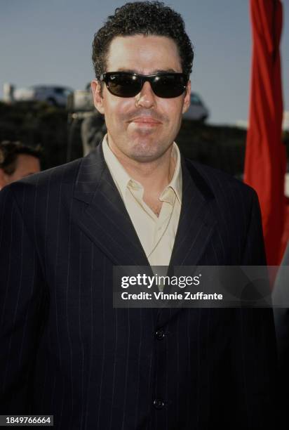 American comedian, actor and radio presenter Adam Carolla, wearing sunglasses, attends the 1999 MTV Movie Awards, held at the Barker Hangar, at Santa...