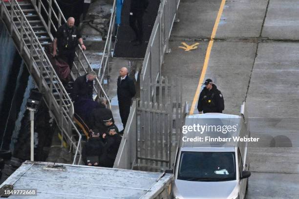 Police officers stand by the steps of the Bibby Stockholm Barge as a body is brought out on a gurney and taken to the funeral van for the coroner on...