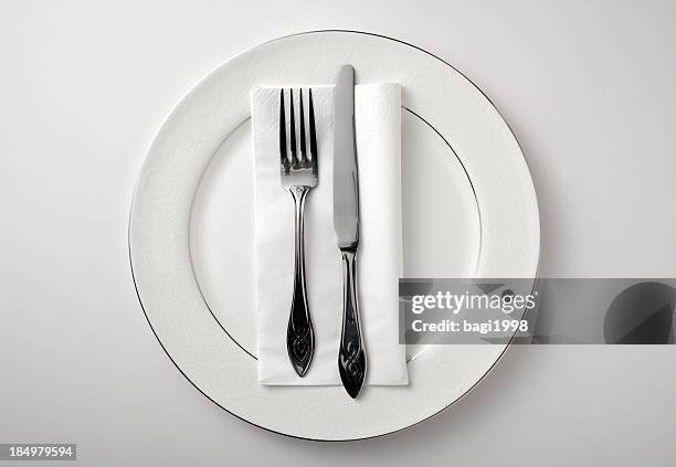 eating utensils on a white plate against a white background - stage set stock pictures, royalty-free photos & images