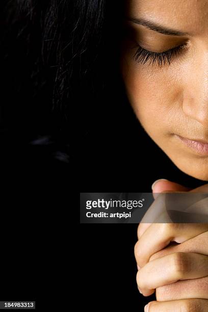 a woman in prayer and a black background - christianity black background stock pictures, royalty-free photos & images