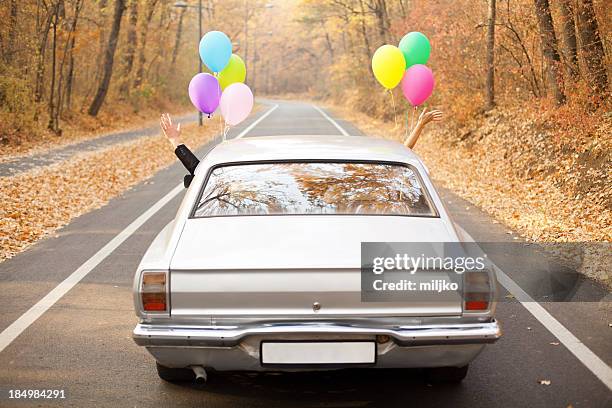 a couple just married with balloons tied to their car - car decoration stock pictures, royalty-free photos & images