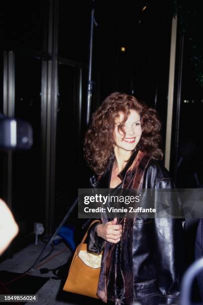 Canadian actress Lolita Davidovich, wearing a black leather jacket and carrying a tan handbag, attends the Century City premiere of 'Nell', held at...