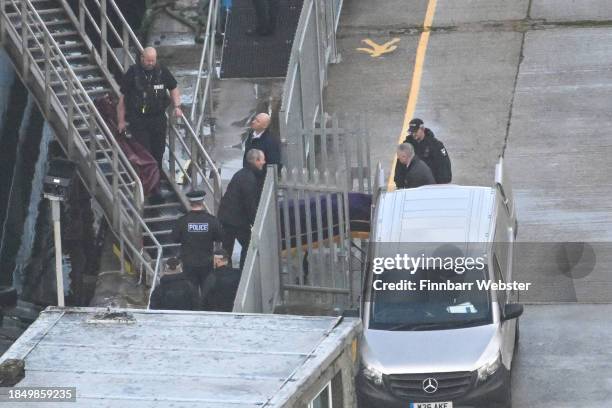 Gurney thought to be carrying the deceased is taken off at Bibby Stockholm Barge on December 12, 2023 in Portland, England. Police are investigating...