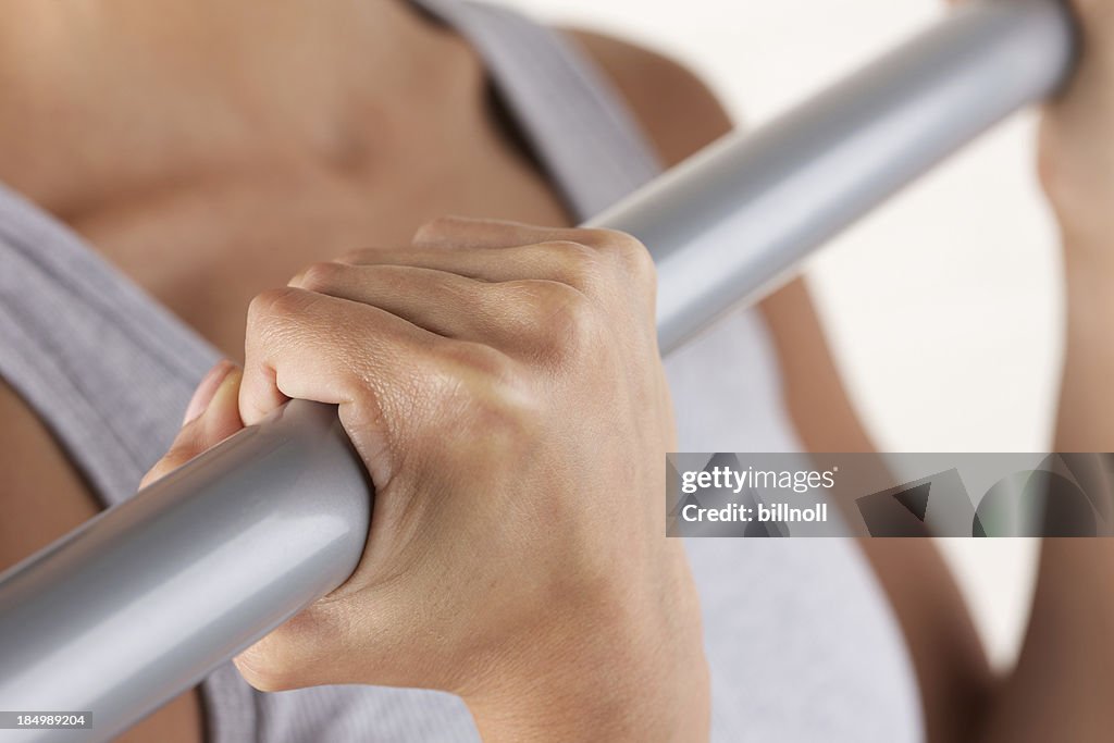 Young woman exercising with metal bar