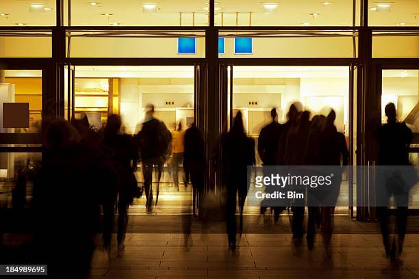 people walking toward illuminated entrance - entrance building people stock pictures, royalty-free photos & images