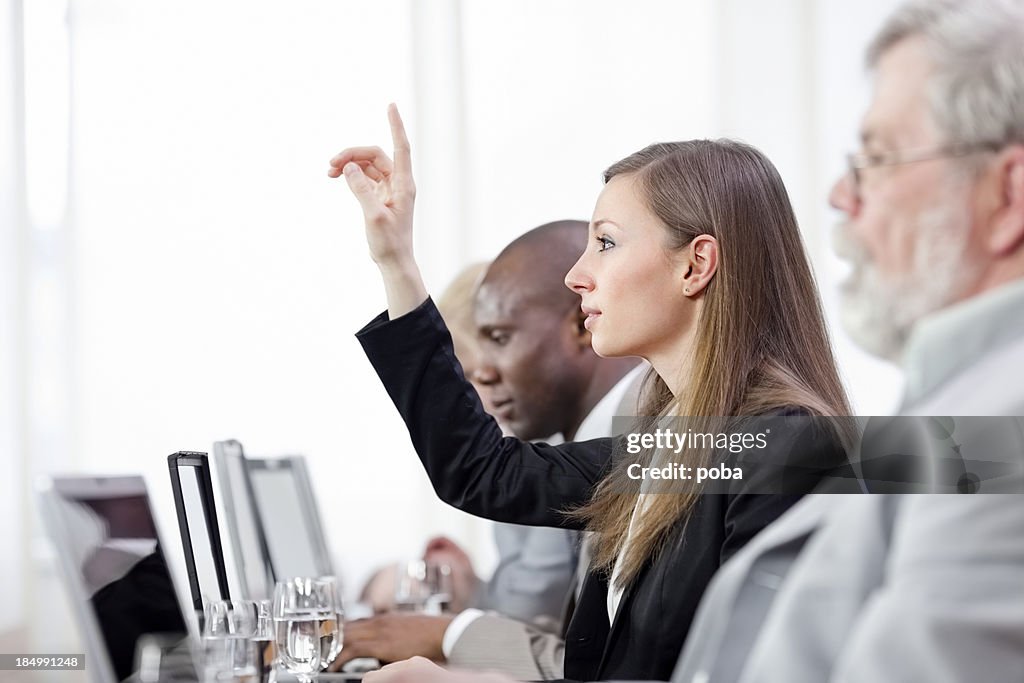 Donna d'affari segnalazione di mano durante una riunione di lavoro