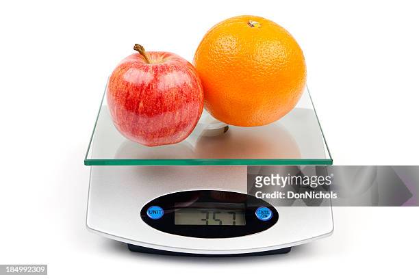 apple and orange on scale - mass unit of measurement stock pictures, royalty-free photos & images