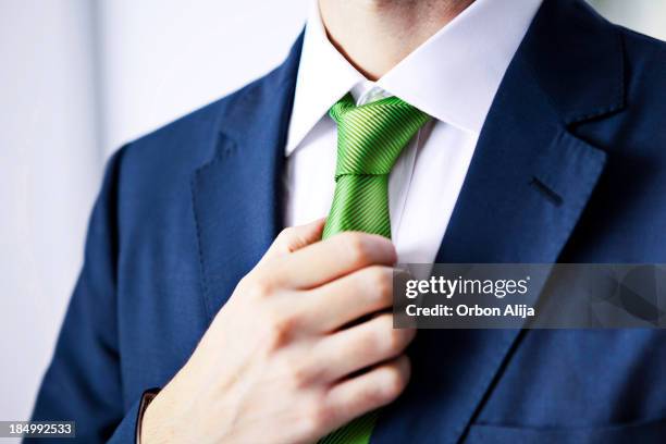 geschäftsmann anpassung krawatte - green body suit stock-fotos und bilder