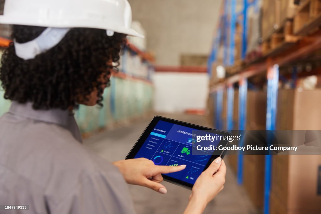 Female engineer using a tablet app to track shipments in a warehouse