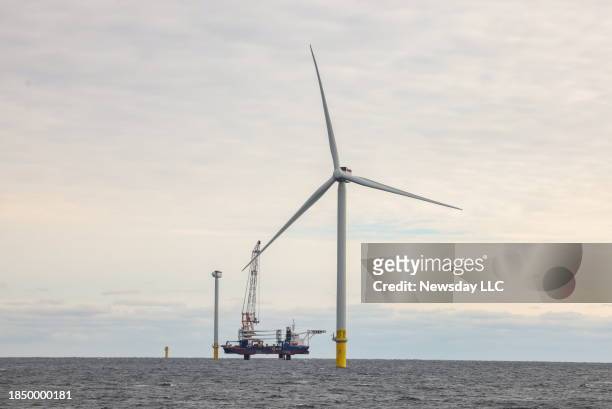 An operational wind turbine, along with two under construction behind it, and a lifting barge, are seen in this photo taken at the South Fork Wind...