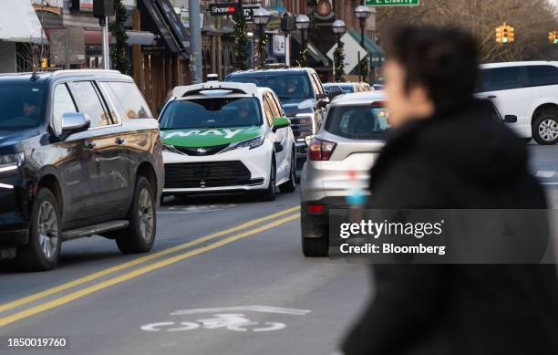 Pedestrians walk past a May Mobility autonomous vehicle shuttle in Ann Arbor, Michigan, US, on Thursday, Dec. 14, 2023. May Mobility, backed by...