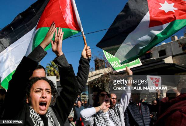 People wave Palestinian and Jordanian flags and chant slogans as they march during a demonstration near the US embassy in the capital Amman in...
