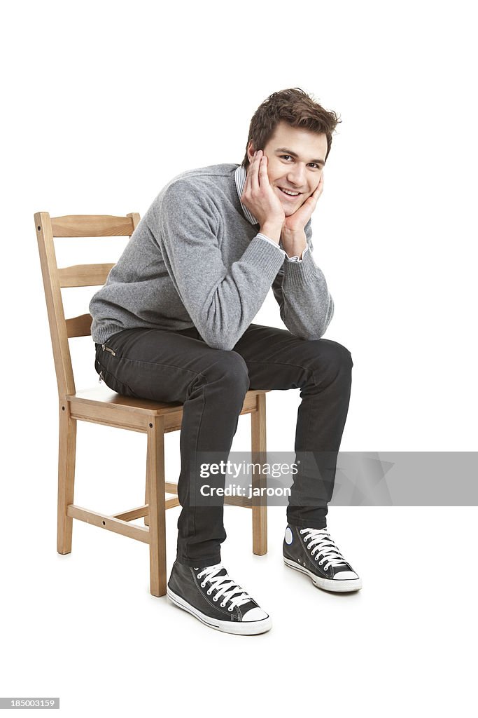 Young handsome man in grey sweater sitting on chair