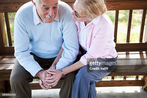 senior woman consoling sad husband. - old couple holding hands stock pictures, royalty-free photos & images
