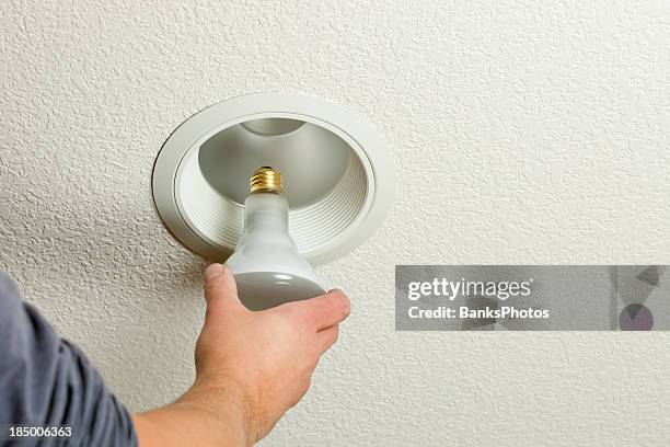 installing incandescent recessed light bulb in ceiling fixture - fitting stockfoto's en -beelden