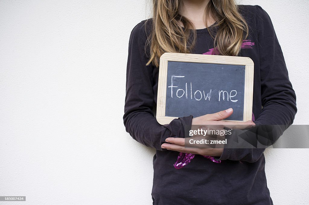 Girl holding sign with Follow me