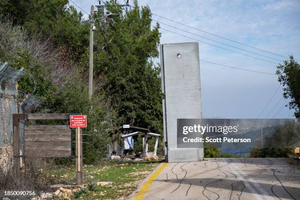 The fortified entrance to Mattat village, with Lebanese territory visible at the end of the road and a red sign claiming the road is a dangerous red...