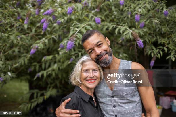 portrait of smiling senior woman and mature man embracing in garden - generation gap stock pictures, royalty-free photos & images