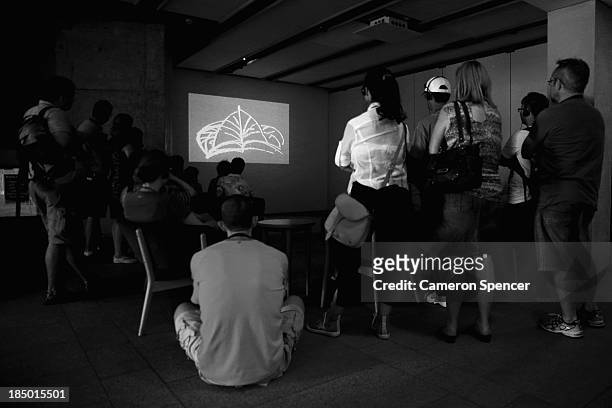 Tourists watch an audio-visual presentation on the design and history of the Sydney Opera House at the Sydney Opera House on September 26, 2013 in...