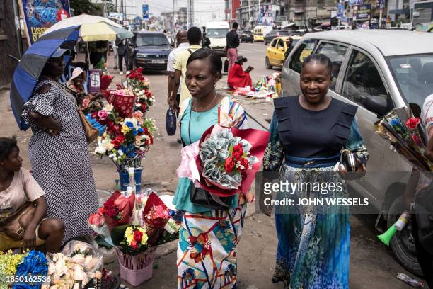 Woman carries a bouquet of roses and money as she heads to congratulate her daughter on her university graduation in Kinshasa on December 15, 2023.