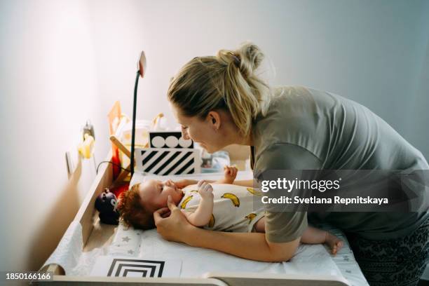 mother changing her newborn son on the changing table - babies only in cloth diapers stock-fotos und bilder