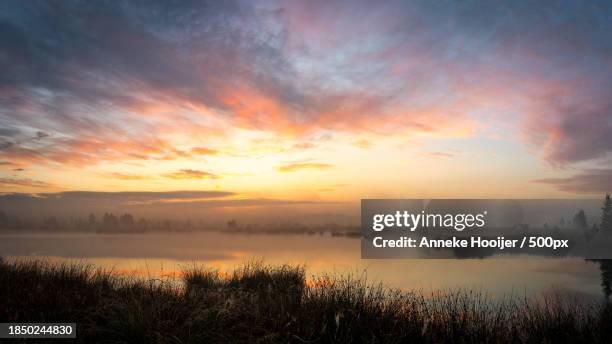 scenic view of lake against sky during sunset - natuurgebied stock-fotos und bilder