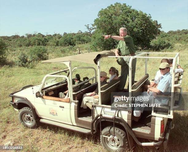 President Bill Clinton and First Lady Hillary Rodham Clinton along with White House aides and Secret Service look at wild animals while on a safari...