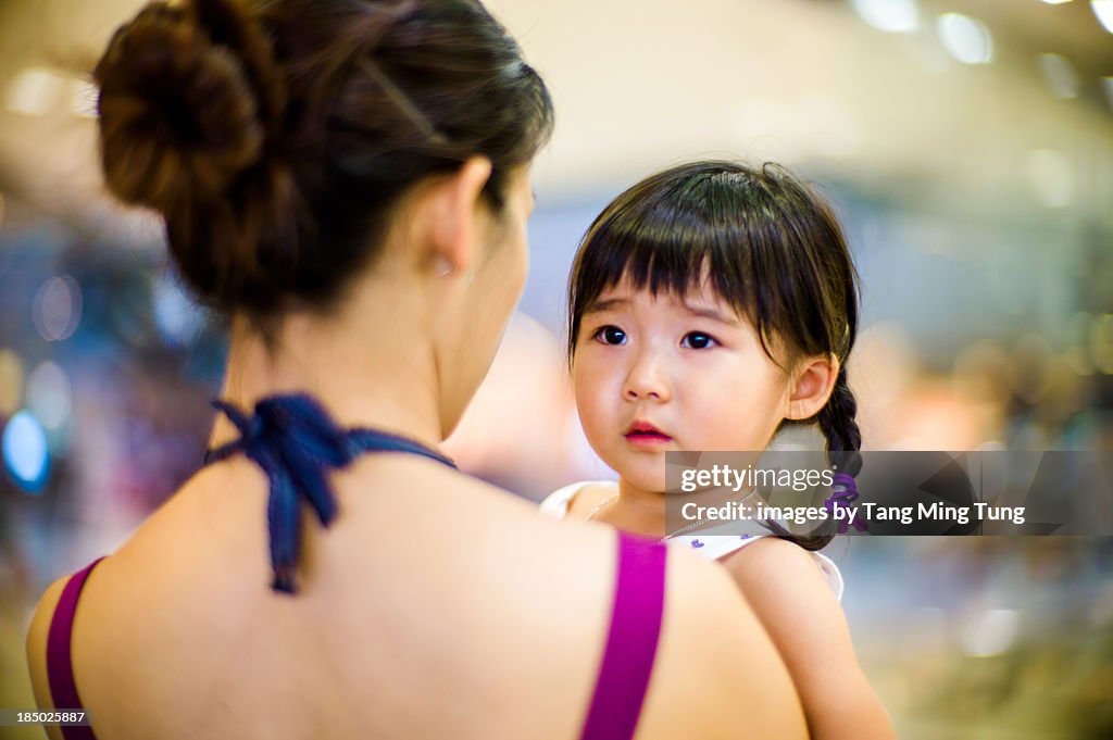 Young mom carrying a sobbing toddler girl