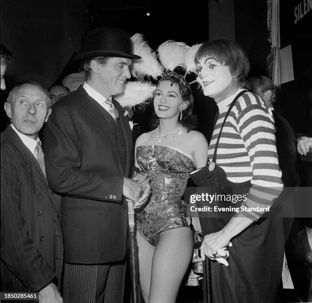 Actors Burt Lancaster , second left, Janette Scott in showgirl outfit and Laurence Olivier , fourth right, in mime artist costume, backstage during...