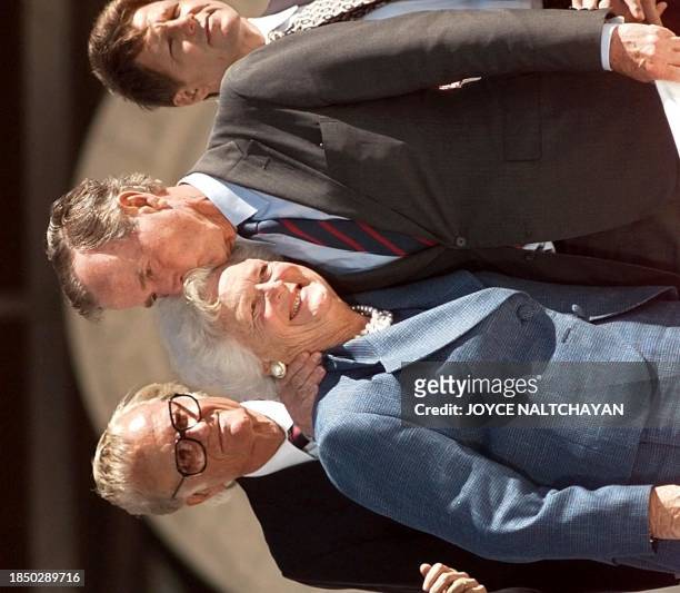 Former US president George Bush kisses his wife Barbara 06 November as preacher Billy Graham looks on at the conclusion of the dedication ceremony of...
