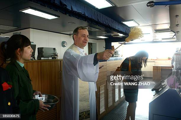 Priest gives a blessing at a wheelhouse of a bulk carrier of Louis Dreyfus Armateurs Group during a naming ceremony for bulk carriers at a shipyard...