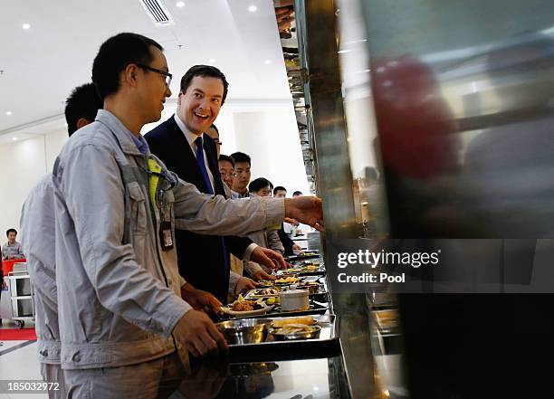 British Chancellor of the Exchequer George Osborne talks with workers as he lunches at a canteen during a visit to a nuclear reactor under...