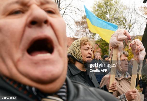 Activists of the Ukrainian public organization Alma Mater shout slogans as they hold 66 chickens carcasses during a protets in the center of the...