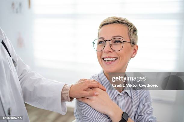 medical practitioner showing support to a female patient, touching her shoulder - hand on shoulder stock pictures, royalty-free photos & images