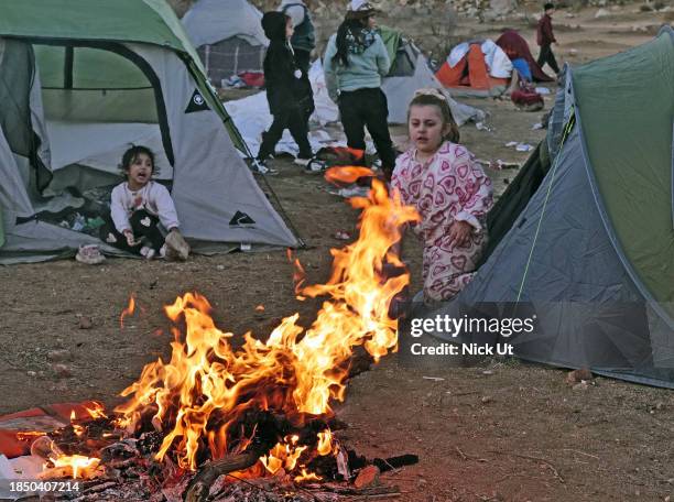 Migrants attempting to cross in to the U.S. From Mexico keep warm in a encampment at the border December 14, 2023 in Jacumba Hot Springs, California....