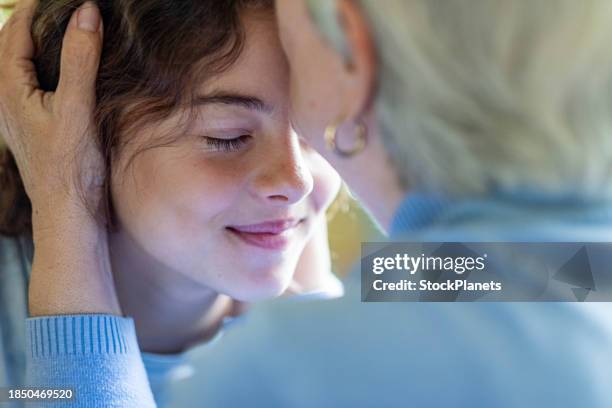 großmutter küsst ihre enkelin auf den kopf - kopf an kopf stock-fotos und bilder