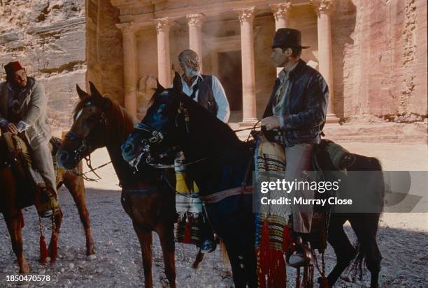 View of, from left, Welsh actor John Rhys-Davies , Scottish actor Sean Connery , and American actor Harrison Ford astride horses in the film 'Indiana...