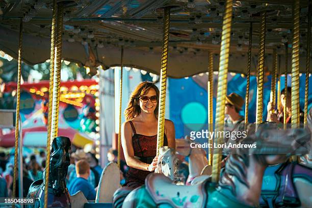 smiling woman riding an old fashion carousel - moving down to seated position stock pictures, royalty-free photos & images
