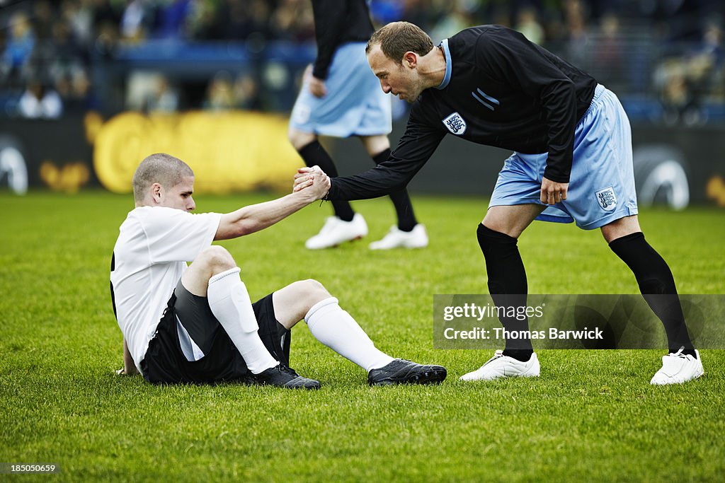 Soccer player helping opposing player up