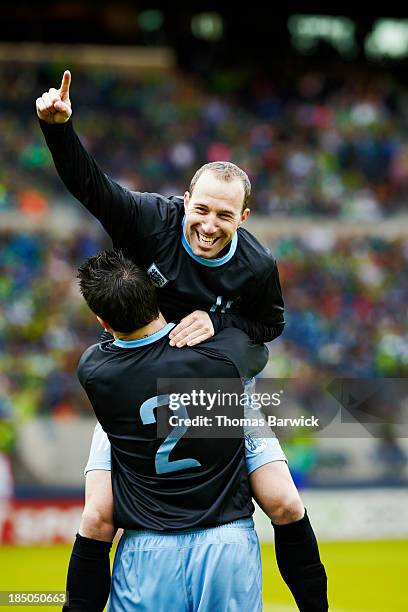 soccer player jumping into the arms of teammate - football player celebrating stock pictures, royalty-free photos & images